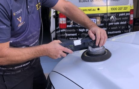 Using machine buffer to apply polish to white car